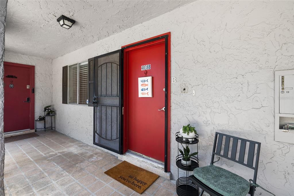 A red front door with a screen door and a welcome mat on a patio — 4038 CORTEZ DRIVE UNIT B, TAMPA, FL