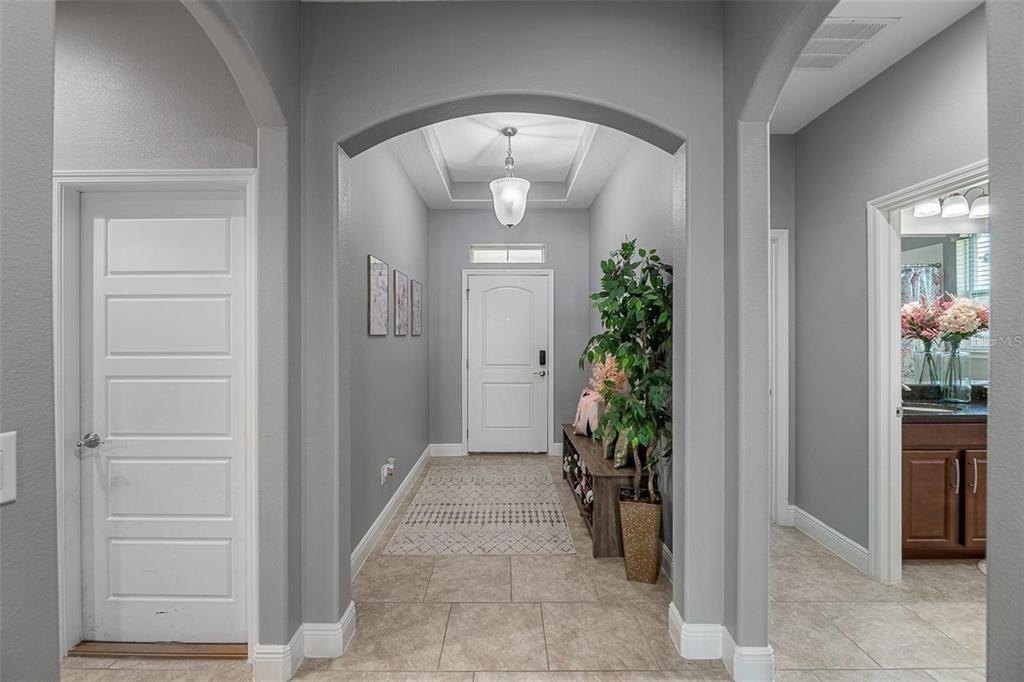 A bright entryway features gray walls, tile flooring, an arched ceiling, and a white door — 4419 LINWOOD TRACE LANE, CLERMONT, FL
