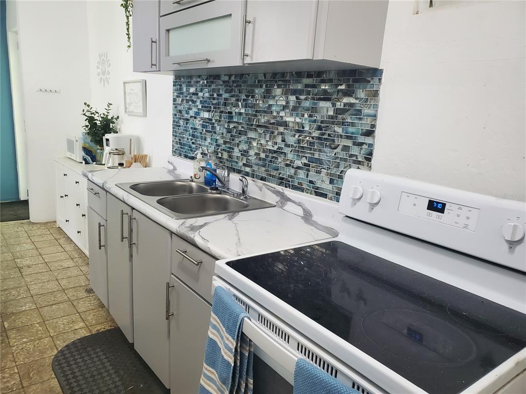 A kitchen features gray cabinets, a marble-look countertop, and a blue glass tile backsplash — 10 CALLE COVALLE GANDIA STREET UNIT 201 B, ARECIBO, PR