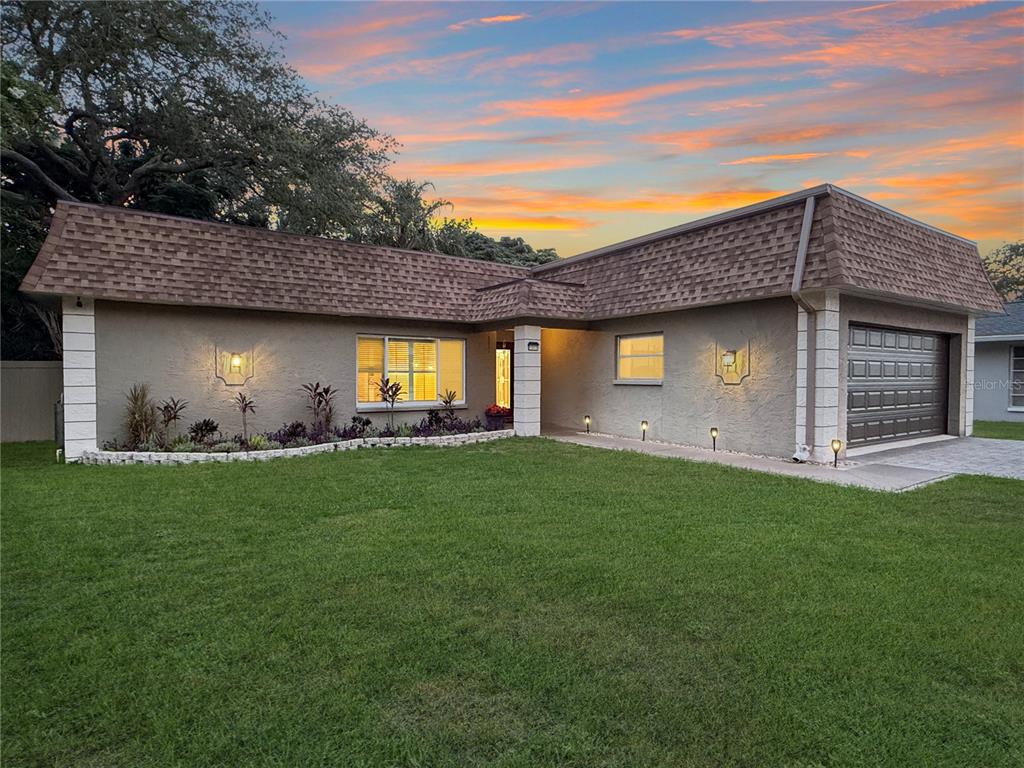 A single-story house with a brown mansard roof, stucco exterior, and a two-car garage — 1011 WINDING OAKS DRIVE, PALM HARBOR, FL