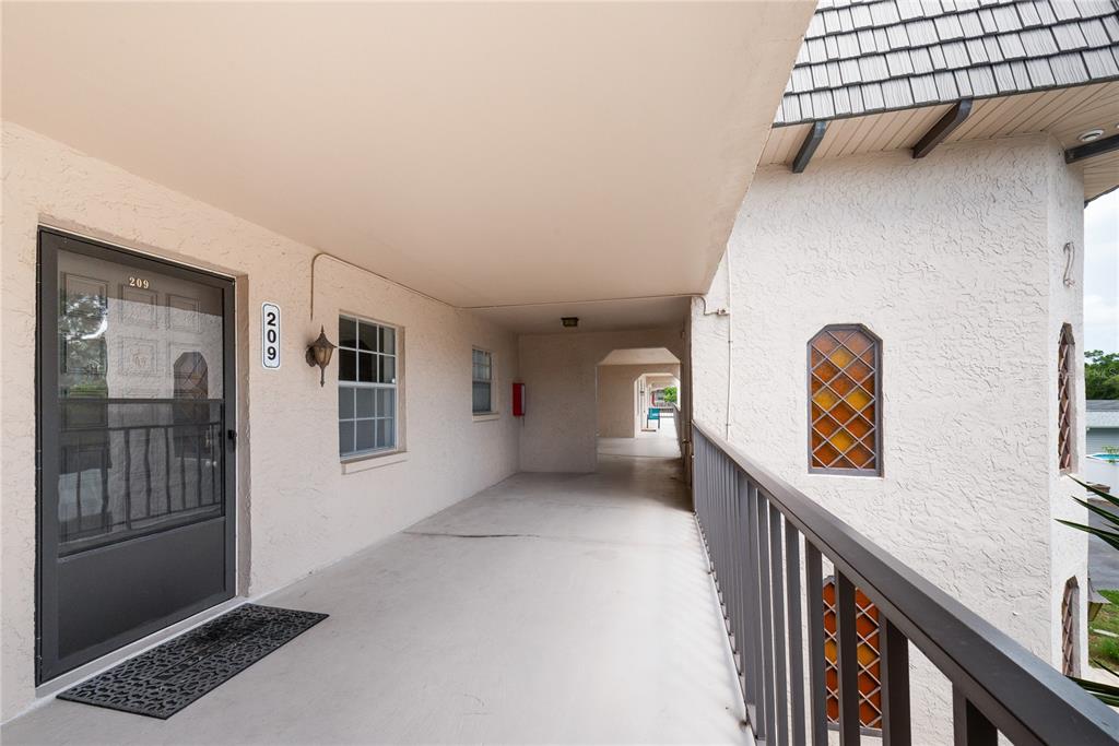 An outdoor apartment walkway features a door labeled 209, a stained-glass window, and railings — 209 CORDOVA GREEN UNIT 209, SEMINOLE, FL