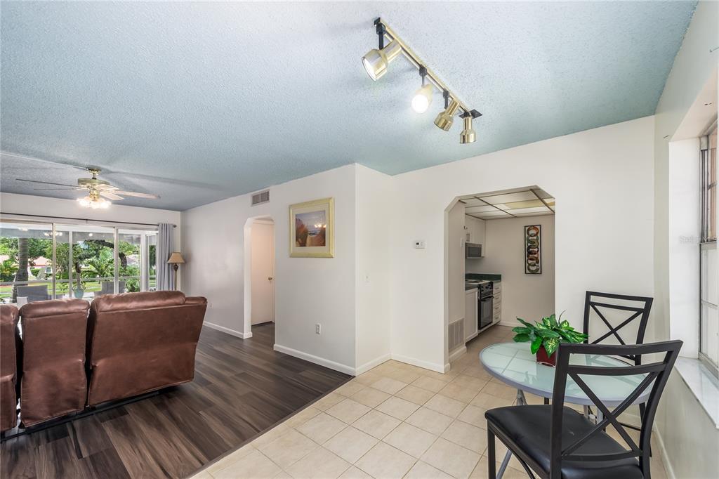 A living room and dining area with wood-look flooring, tile, and a view of the outdoors — 209 CORDOVA GREEN UNIT 209, SEMINOLE, FL