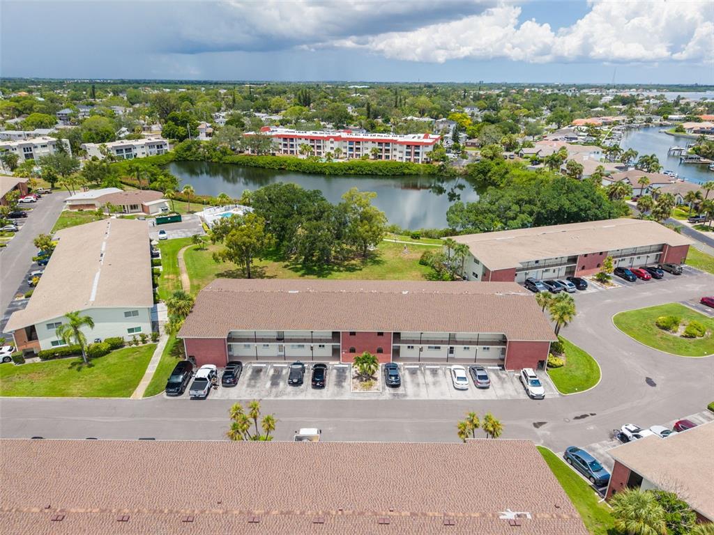 An aerial view shows several multi-story apartment buildings surrounding a central pond and parking lots — 4550 OVERLOOK DRIVE NE UNIT 152, ST PETERSBURG, FL