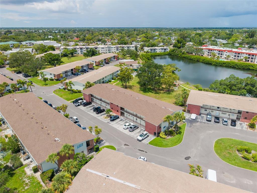 An aerial view shows several multi-story apartment buildings surrounding a pond and parking lots — 4550 OVERLOOK DRIVE NE UNIT 152, ST PETERSBURG, FL