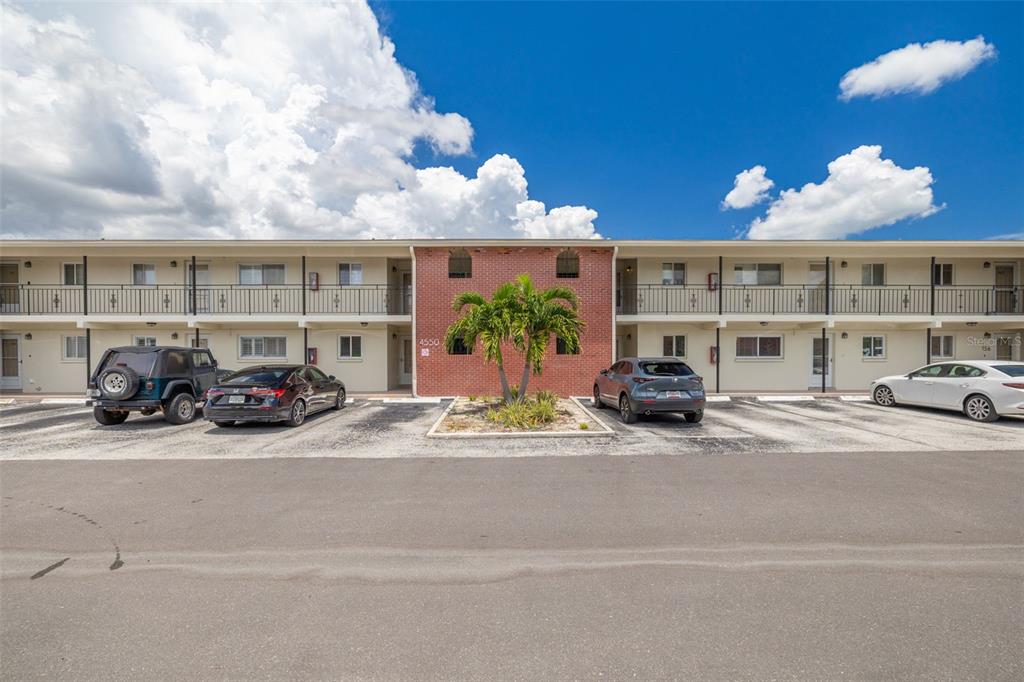 A two-story apartment building with a brick center section, palm tree, and parking lot — 4550 OVERLOOK DRIVE NE UNIT 152, ST PETERSBURG, FL