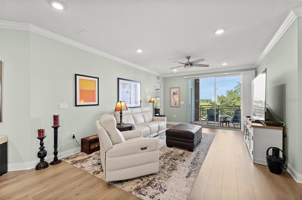A modern kitchen features white cabinetry, stainless steel appliances, and wood-look flooring — 7505 LAUREATE BOULEVARD UNIT 2206, ORLANDO, FL
