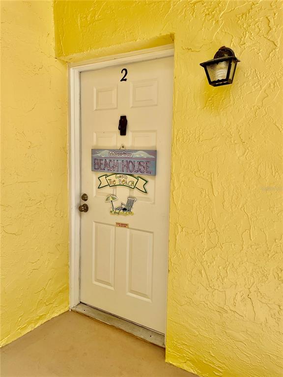A white door labeled with the number two is set into a yellow stucco wall — 594 N WICKHAM ROAD UNIT 2, MELBOURNE, FL