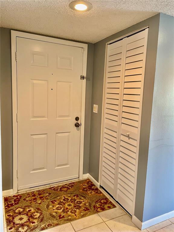 An entryway features a white six-panel door, a louvered closet, and a patterned rug — 594 N WICKHAM ROAD UNIT 2, MELBOURNE, FL