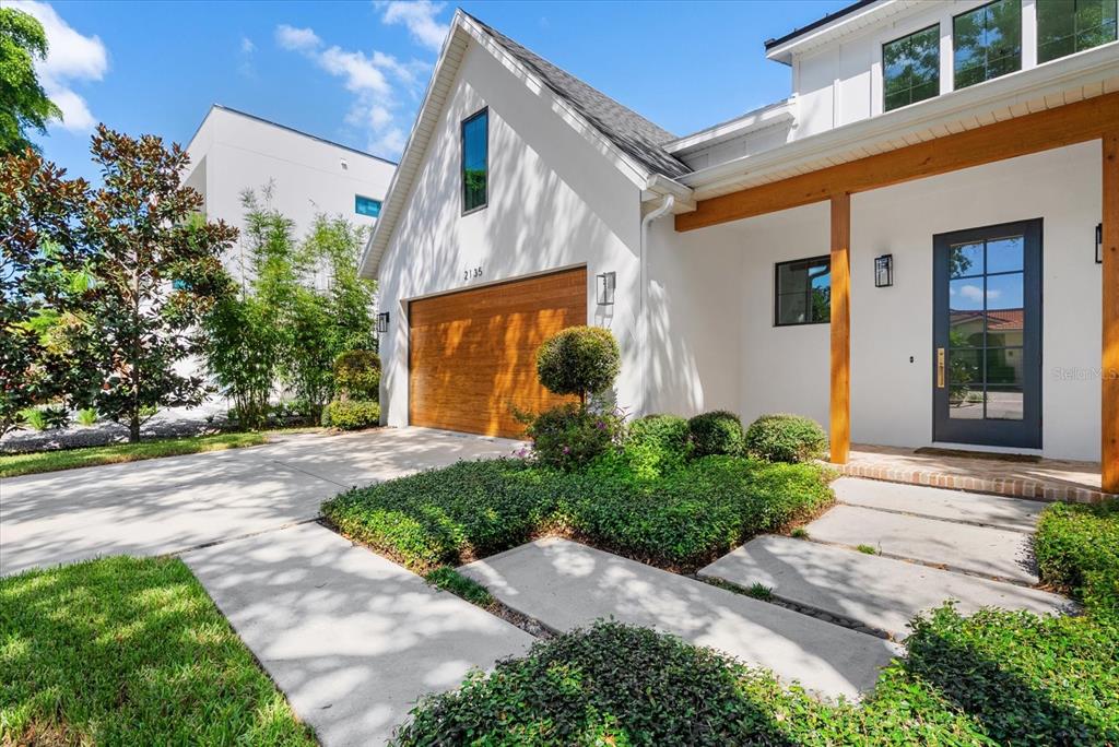 A white house exterior features a wooden beam porch, a dark door, and stone pavers — 2135 DATURA STREET, SARASOTA, FL