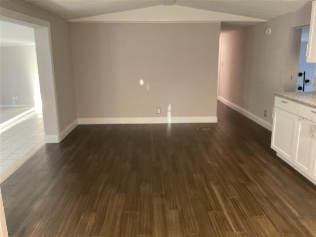 An interior view of a room with dark wood-look flooring and light gray walls — 5038 NE SANDY ROAD, ARCADIA, FL