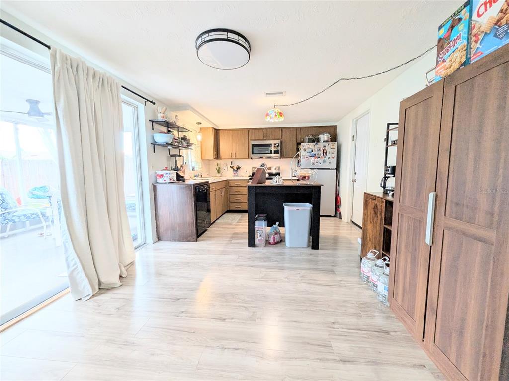A kitchen features wood cabinets, a central island, and light-colored wood-look flooring — 3748 REDWOOD DRIVE, HOLIDAY, FL