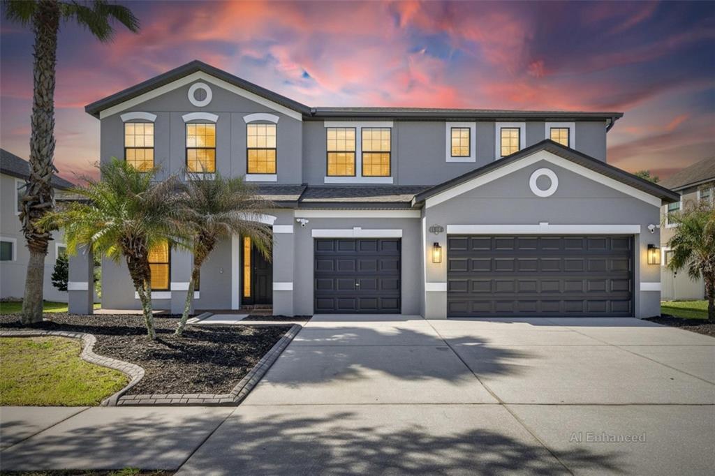 A two-story gray house with a two-car garage and a paved driveway at sunset — 11807 HARPSWELL DRIVE, RIVERVIEW, FL