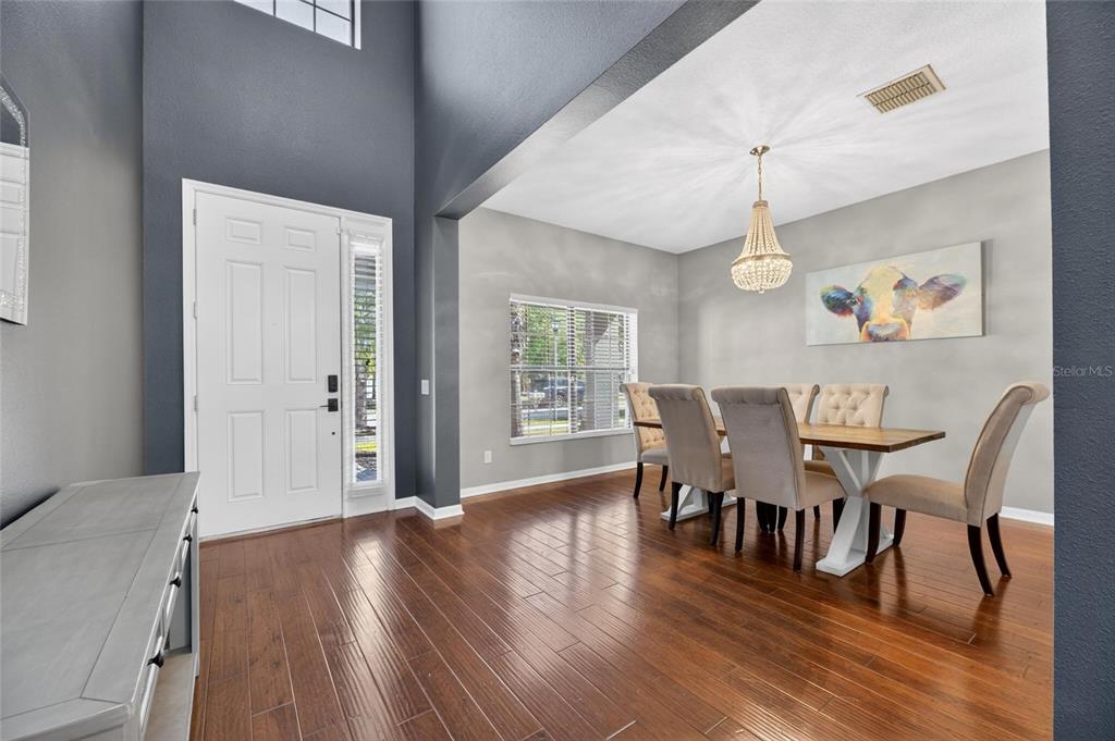A dining room with hardwood floors, a crystal chandelier, and a cow painting on the wall — 11807 HARPSWELL DRIVE, RIVERVIEW, FL