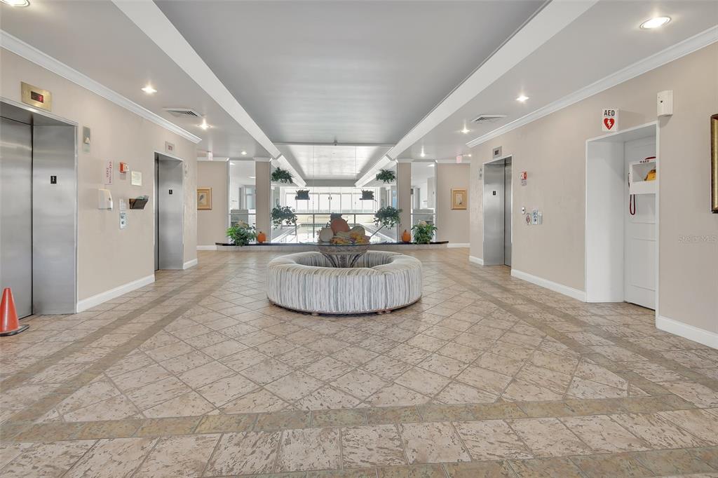 A building lobby features a circular ottoman, tiled floors, and two sets of elevators — 2937 S ATLANTIC AVENUE UNIT 708, DAYTONA BEACH SHORES, FL