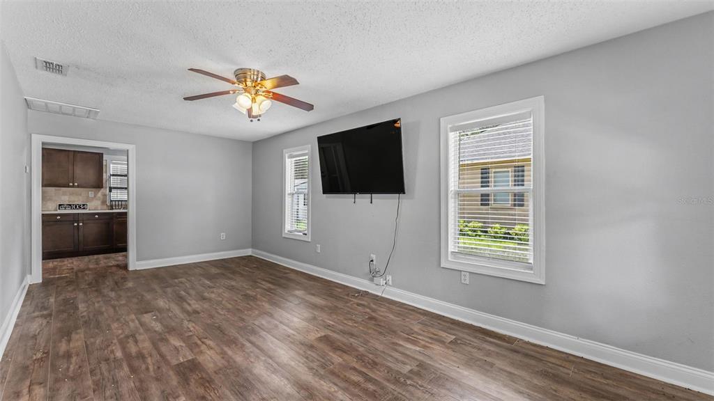 A living room with gray walls, wood-look flooring, a ceiling fan, and a wall-mounted television — 1034 S DAKOTA AVENUE, LAKELAND, FL