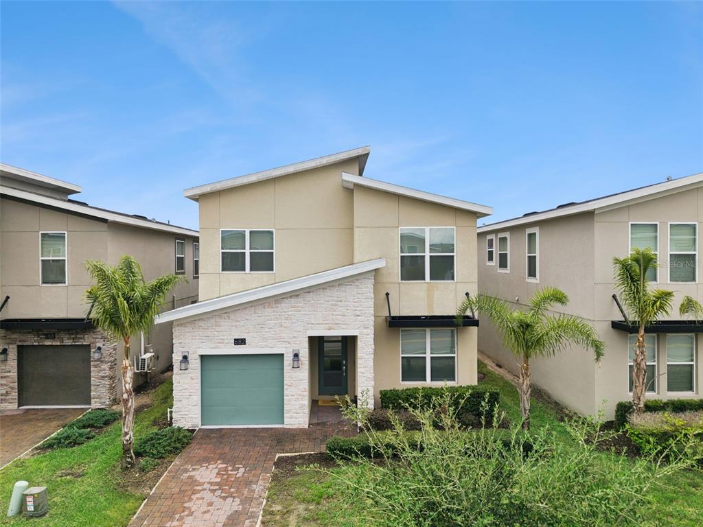 A two-story house with a stone facade, a green garage door, and palm trees — 682 WHISTLING STRAITS BOULEVARD, DAVENPORT, FL