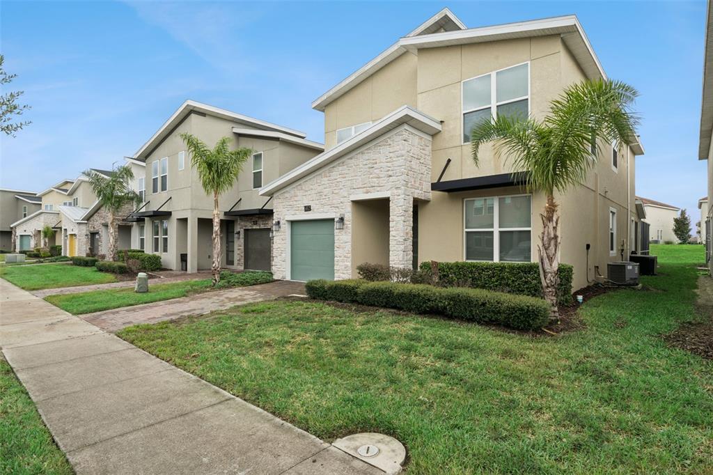 A two-story suburban house with a stone facade, green garage door, and a front lawn — 682 WHISTLING STRAITS BOULEVARD, DAVENPORT, FL