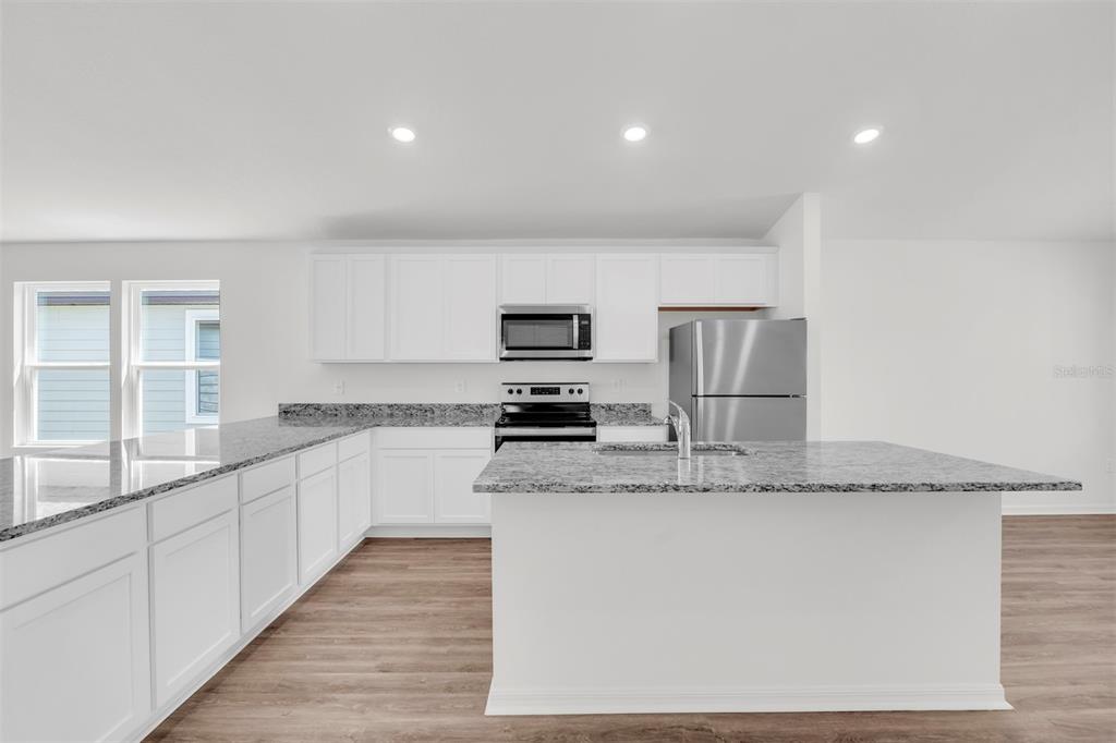 A kitchen with white cabinets, granite countertops, stainless steel appliances, and a central island — 11 PRINCE ANTHONY LANE, PALM COAST, FL