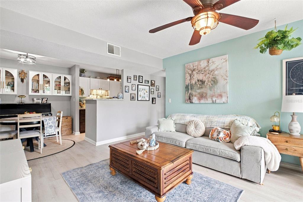 A living room with a light blue accent wall, gray sofa, and wooden coffee table — 455 ALT 19 S UNIT 17, PALM HARBOR, FL