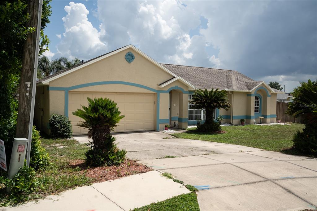 A single-story suburban house with a tan stucco exterior, blue trim, and a two-car garage — 832 WHITE BIRCH COURT, ORANGE CITY, FL