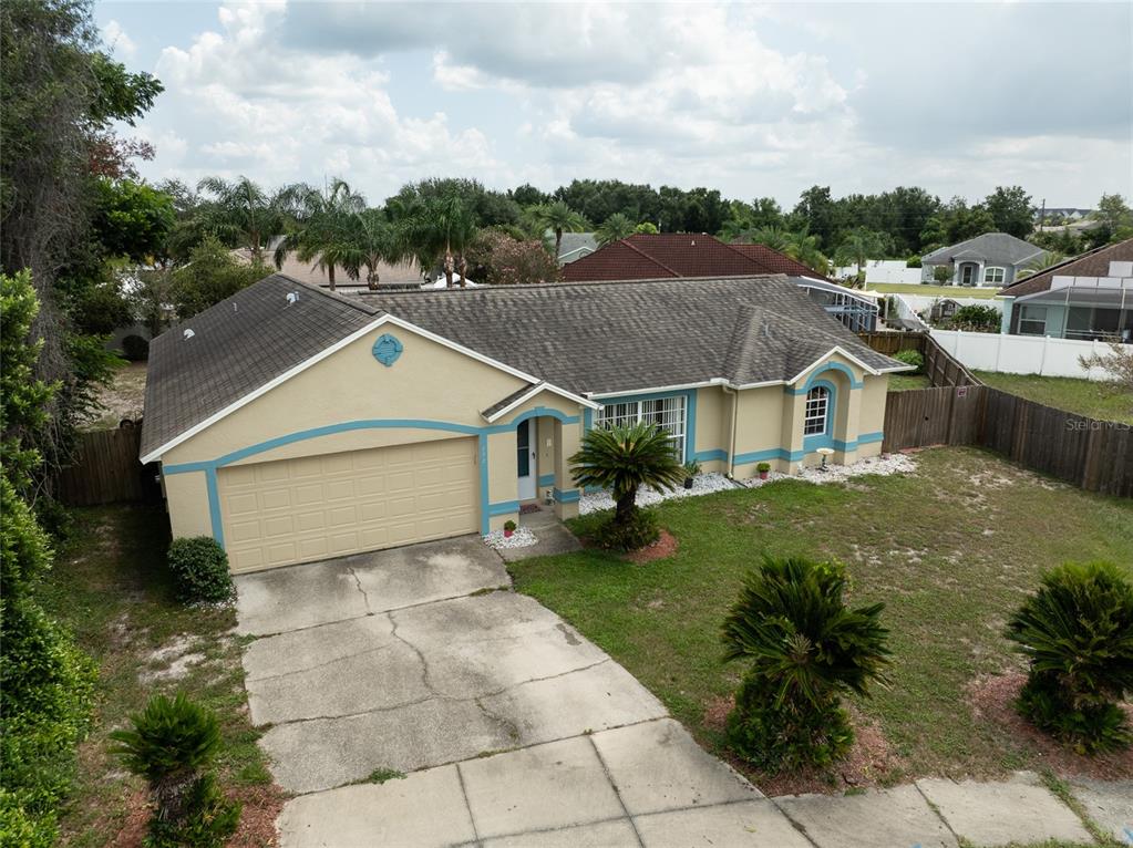 An aerial view of a single-story house with a tan exterior, blue trim, and driveway — 832 WHITE BIRCH COURT, ORANGE CITY, FL