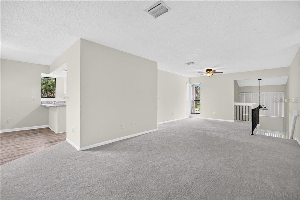 An open living area features gray carpeting, light-colored walls, and a partial wall partition — 22 OXFORD LANE UNIT 22, PALM COAST, FL
