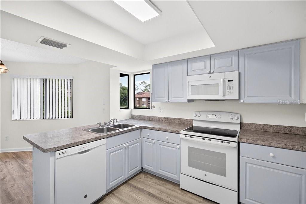 A kitchen features light blue cabinets, white appliances, and a laminate countertop with a sink — 22 OXFORD LANE UNIT 22, PALM COAST, FL