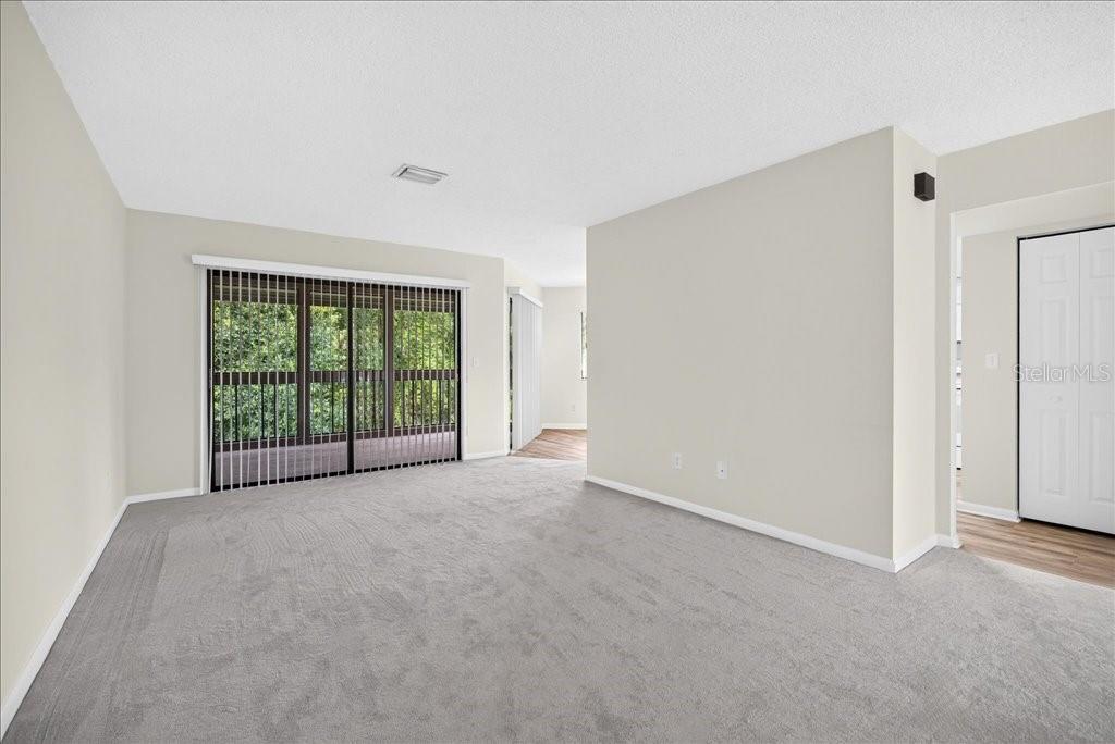 An empty living room features gray carpeting, light walls, and sliding glass doors — 22 OXFORD LANE UNIT 22, PALM COAST, FL