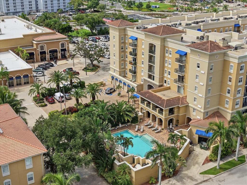 An aerial view shows a multi-story tan building with a swimming pool and palm trees — 1064 N TAMIAMI TRAIL UNIT 1206, SARASOTA, FL