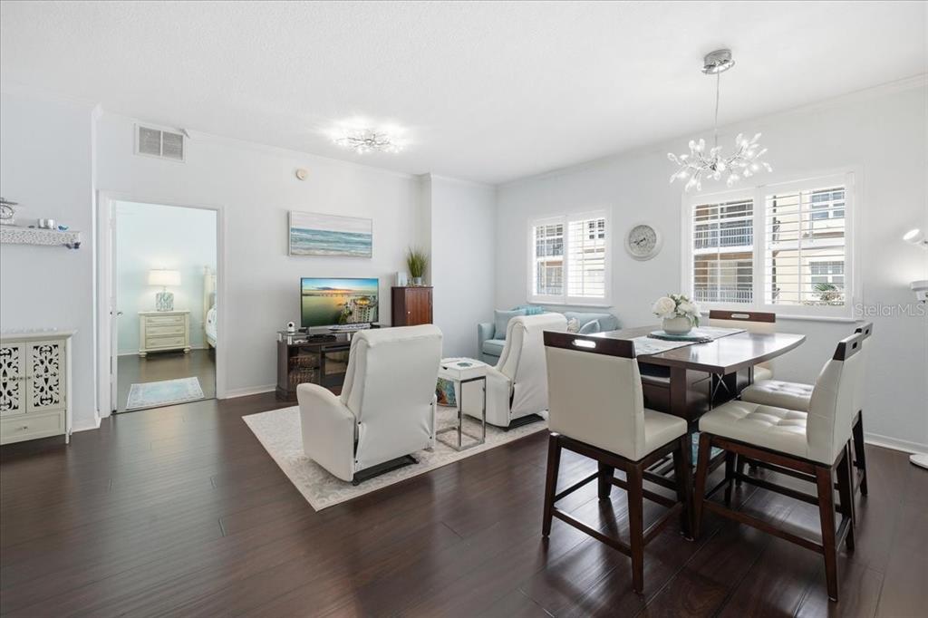A living and dining area with white furniture, dark wood floors, and a chandelier — 1064 N TAMIAMI TRAIL UNIT 1206, SARASOTA, FL