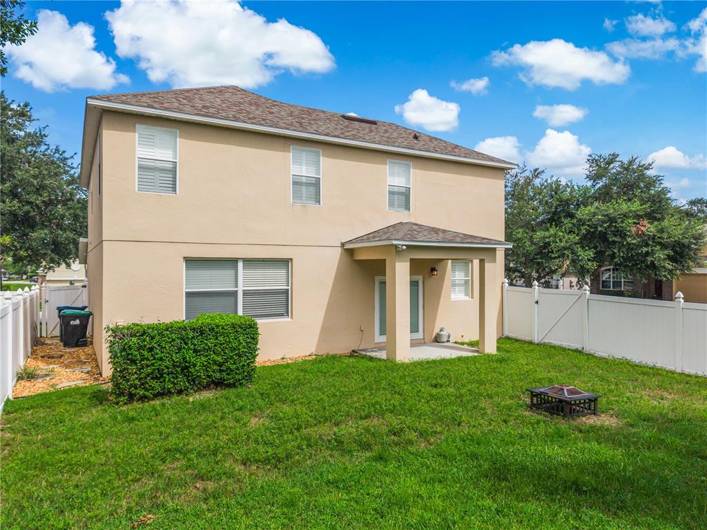 The exterior of a two-story tan house features a covered patio and a fenced backyard — 3906 QUARTZ AVENUE, ORLANDO, FL