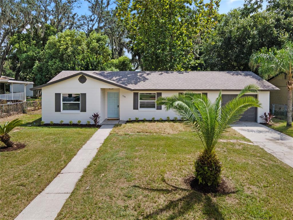A single-story house with white brick, a light blue door, and a front yard — 530 GEORGIA AVENUE, LONGWOOD, FL