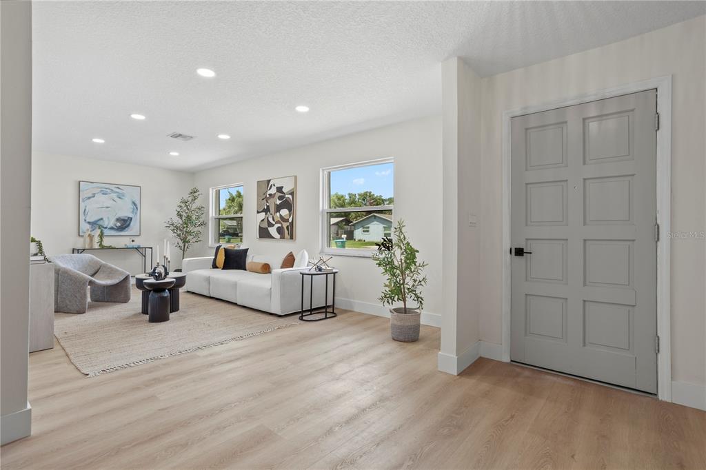 A bright living room features light wood flooring, white walls, recessed lighting, and a gray door — 530 GEORGIA AVENUE, LONGWOOD, FL