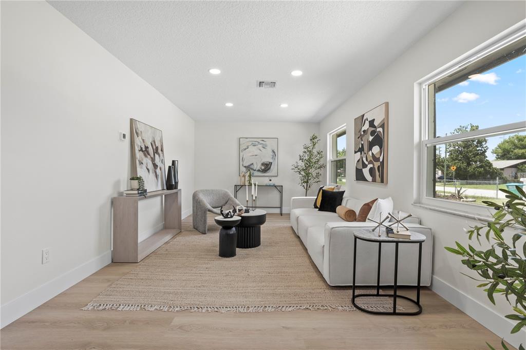 A bright living room features a white sofa, a jute rug, and light wood flooring — 530 GEORGIA AVENUE, LONGWOOD, FL