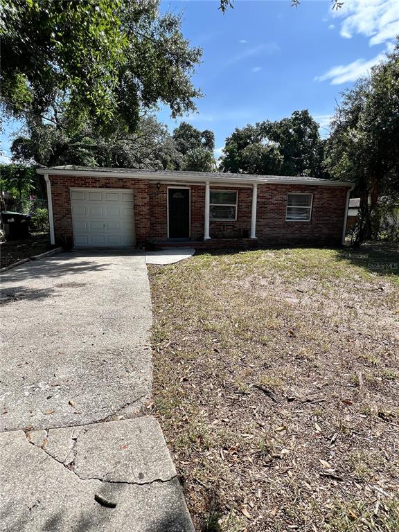 A single-story brick house features a white garage door, a front entrance, and a concrete driveway — 1011 SANTA BARBARA ROAD, ORLANDO, FL