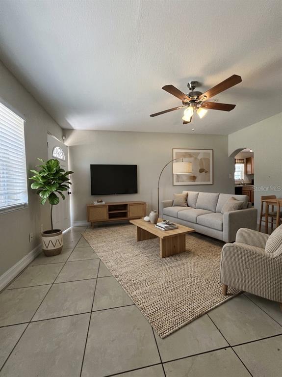 A living room features tile floors, a neutral sofa, a wooden coffee table, and a television — 1011 SANTA BARBARA ROAD, ORLANDO, FL