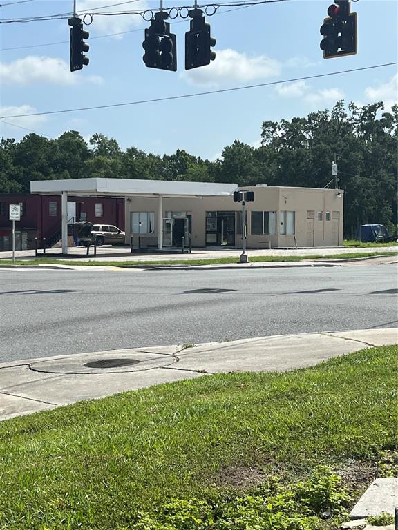 A vacant gas station with a white canopy stands behind a paved road and sidewalk — 100 PONCE DE LEON BOULEVARD, BROOKSVILLE, FL