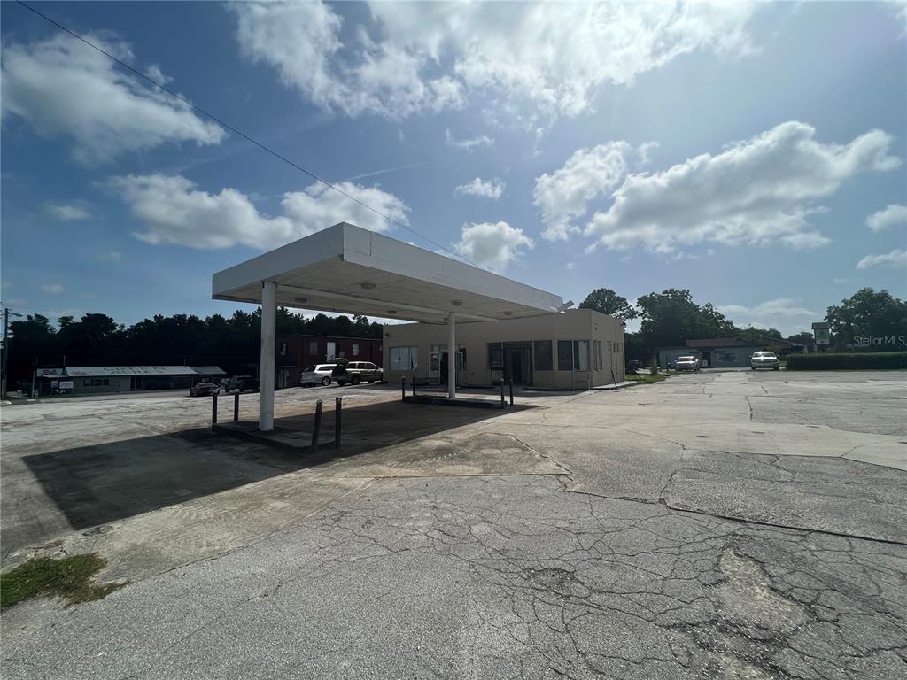 An exterior view of a vacant gas station with a large concrete canopy and parking lot — 100 PONCE DE LEON BOULEVARD, BROOKSVILLE, FL