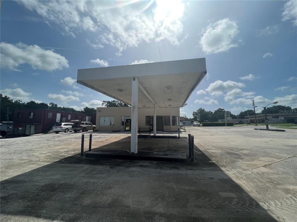An exterior view of a vacant gas station with a large canopy and concrete lot — 100 PONCE DE LEON BOULEVARD, BROOKSVILLE, FL