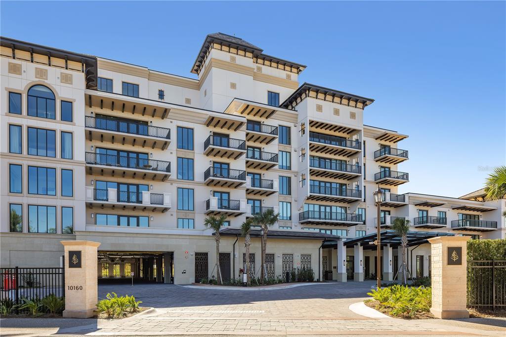 A multi-story apartment building with balconies and a gated entrance driveway — 10160 AUTUMN MIST LANE UNIT 205, ORLANDO, FL
