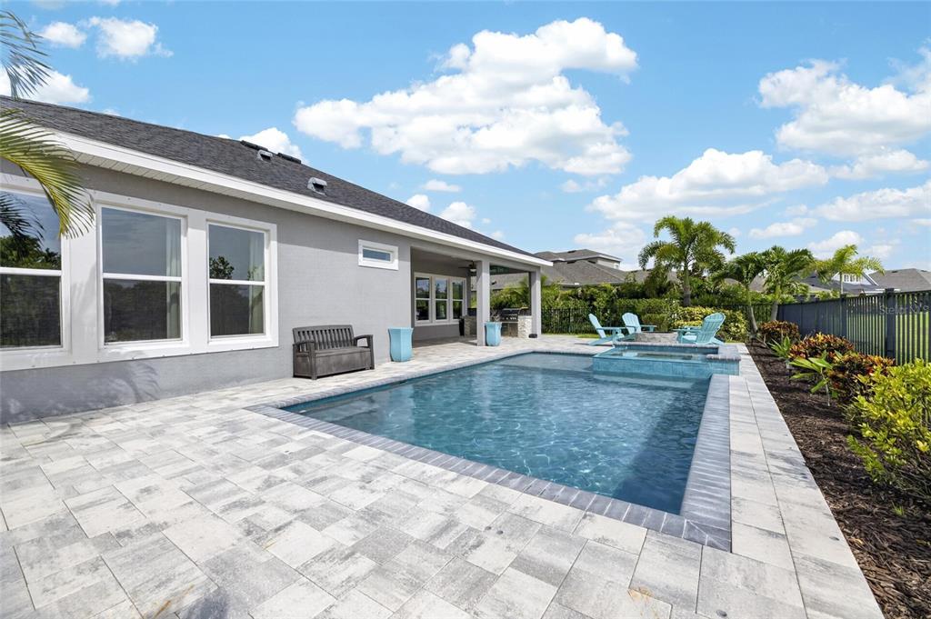 A backyard features a rectangular swimming pool, a spa, and a paved patio area — 7322 PARADISO DRIVE, APOLLO BEACH, FL
