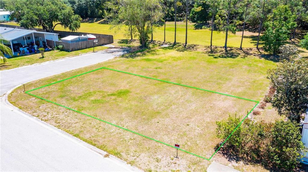 An aerial view shows a vacant, rectangular residential lot outlined in green on a street — CHRIS DR., WESLEY CHAPEL, FL