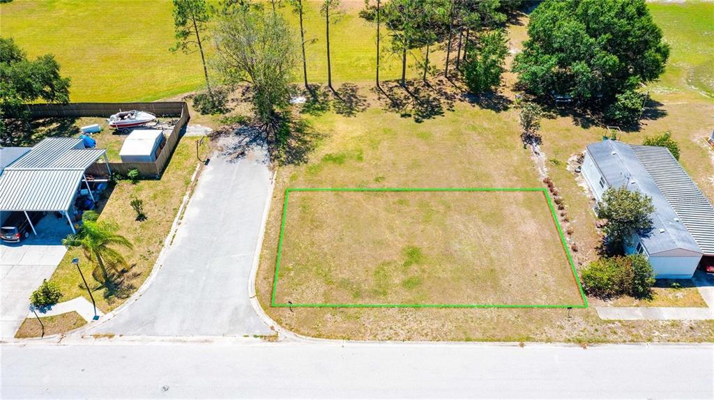 An aerial view shows a vacant rectangular lot outlined in green next to two houses — CHRIS DR., WESLEY CHAPEL, FL