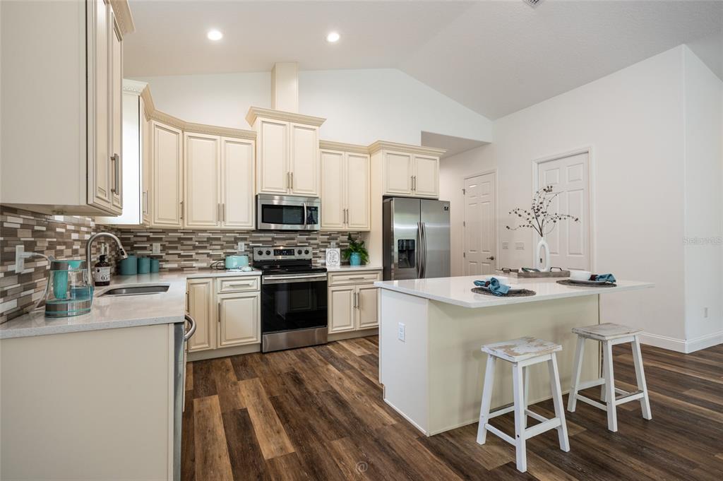 A kitchen features cream cabinets, stainless steel appliances, a center island, and wood-look flooring — 59 GREEN CIRCLE, PALM COAST, FL