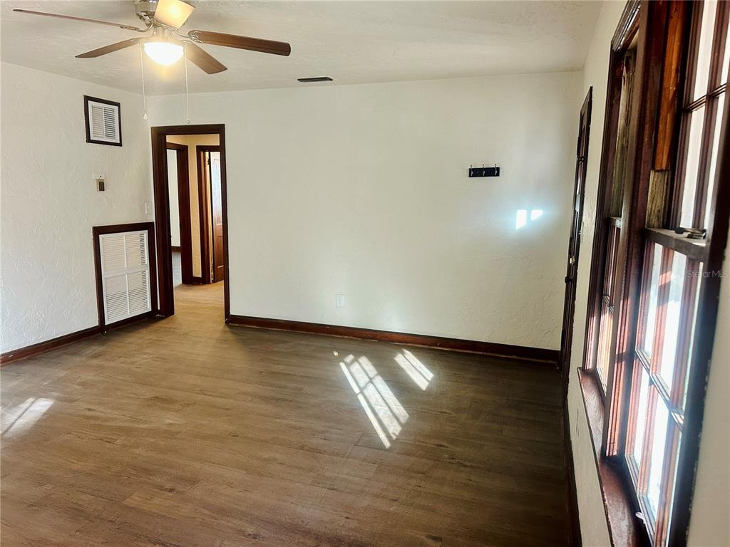 An interior room with wood-look flooring, white walls, a ceiling fan, and large windows — 228 NW 4TH AVENUE, GAINESVILLE, FL