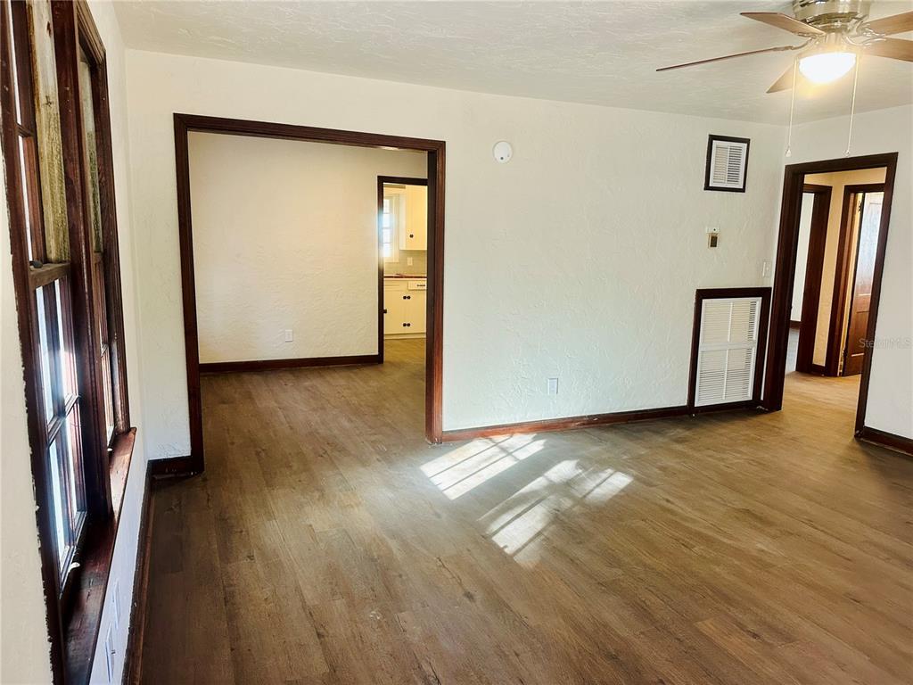 An interior view of a living room with wood-look flooring, white walls, and dark trim — 228 NW 4TH AVENUE, GAINESVILLE, FL