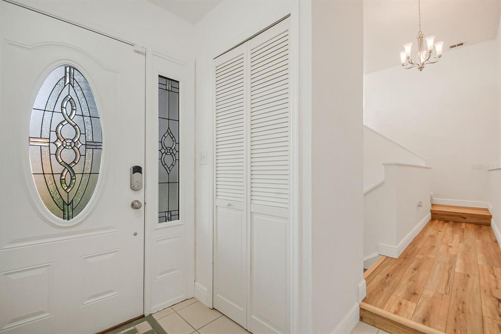 An entryway features a white front door with a glass insert, a closet, and wooden stairs — 2614 CREST DRIVE, HAINES CITY, FL