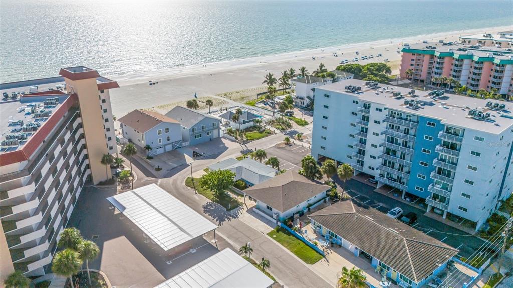 An aerial view shows beachside apartment buildings, parking structures, and houses near the ocean — 18317 SUNSET BOULEVARD, REDINGTON SHORES, FL