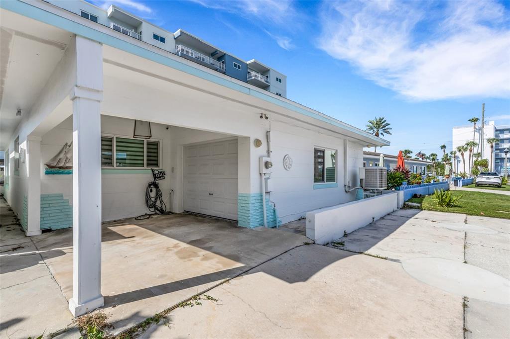 A white one-story building features a covered carport, a garage door, and light blue accents — 18317 SUNSET BOULEVARD, REDINGTON SHORES, FL