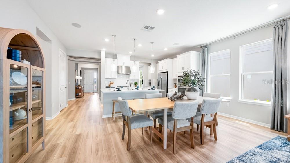 A bright, open-concept kitchen and dining area features light wood flooring and white cabinetry — 5441 GUNWALE DRIVE, COCOA, FL